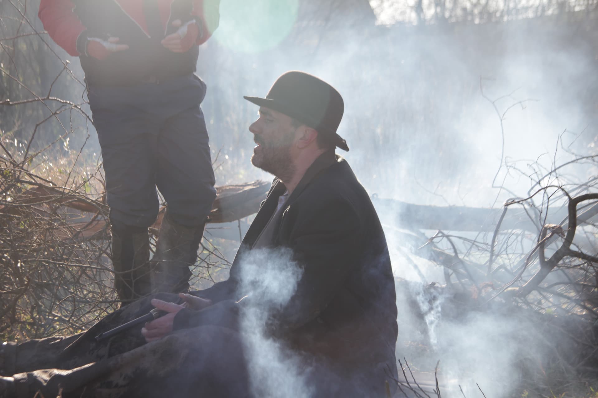 Actor seated beside the fire with a revolver during a take