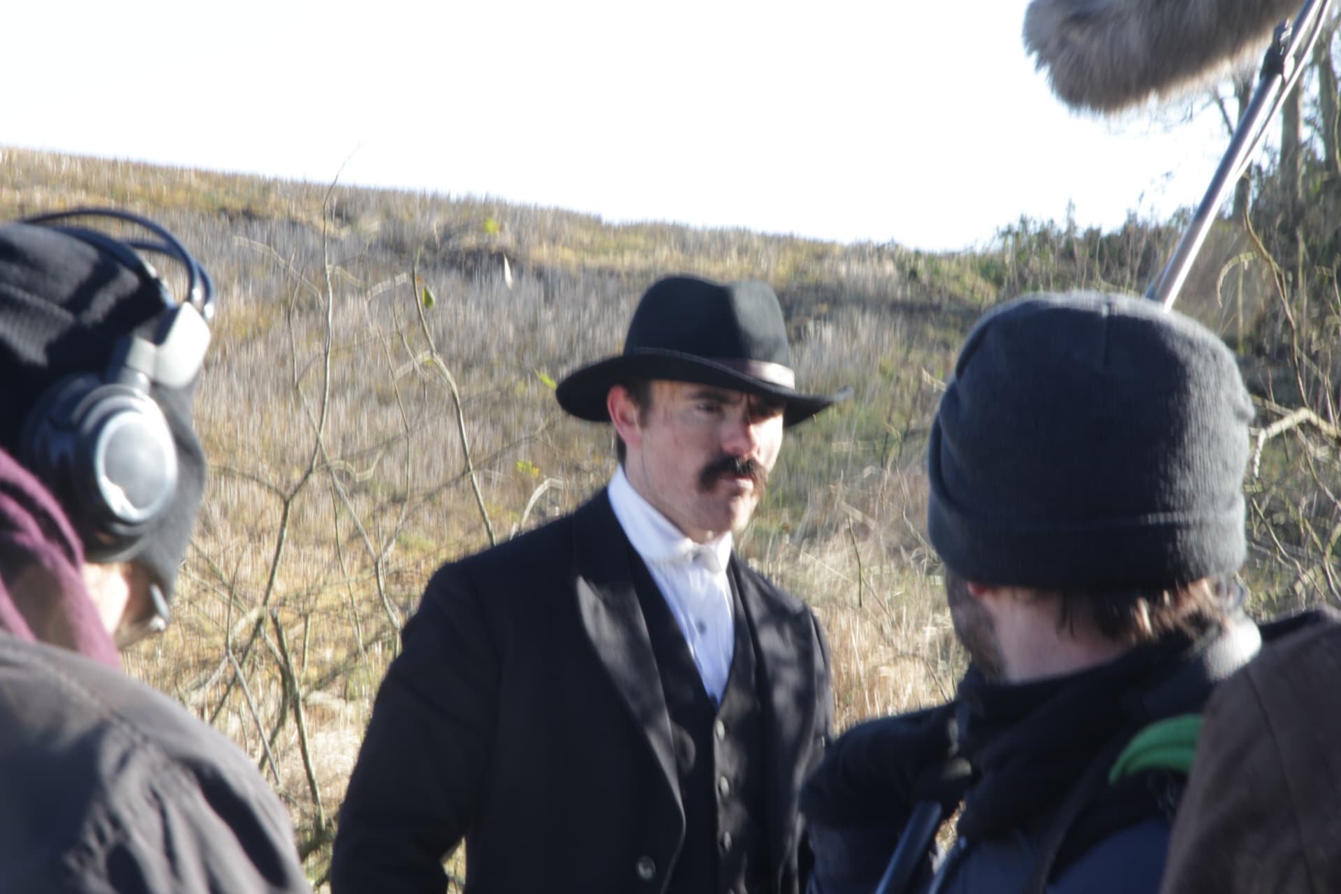 Sound recordist and crew surrounding the lead actor between takes