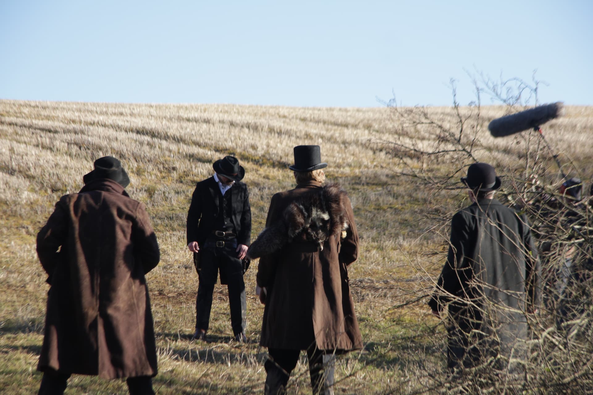 Cast gathered in the stubble field with the boom operator overhead