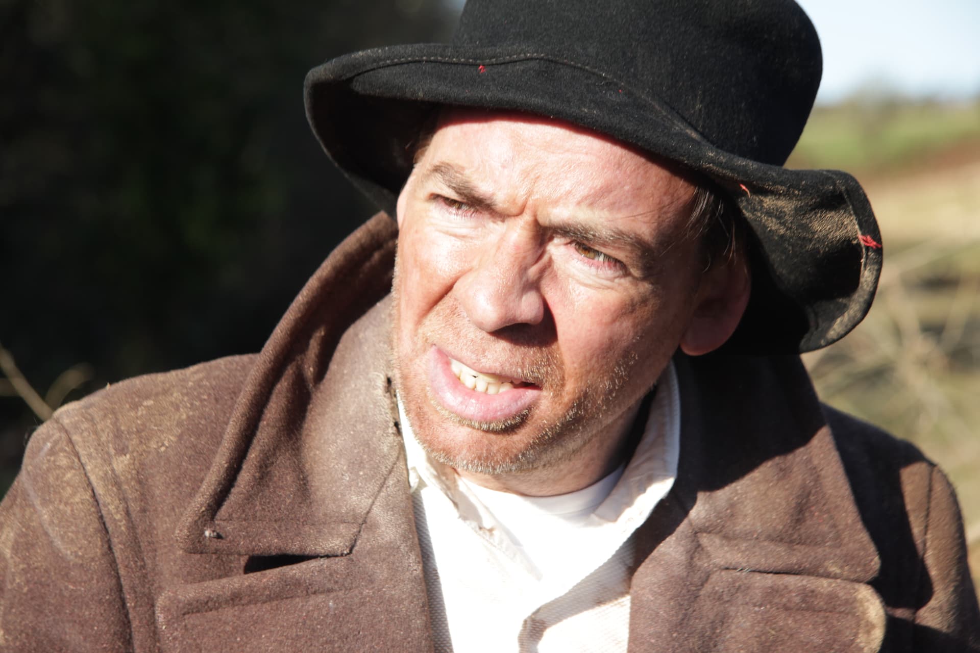 Close-up of a cast member in costume squinting into the winter sun