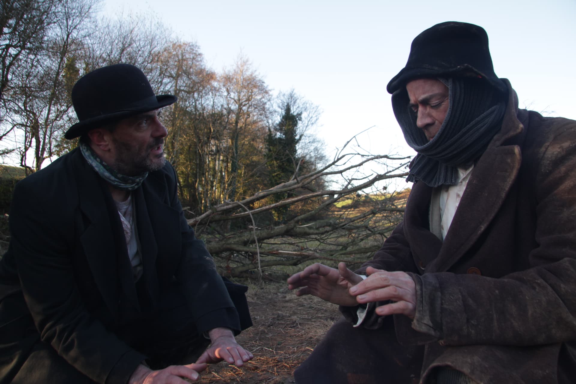 Two actors in period costume between takes on location