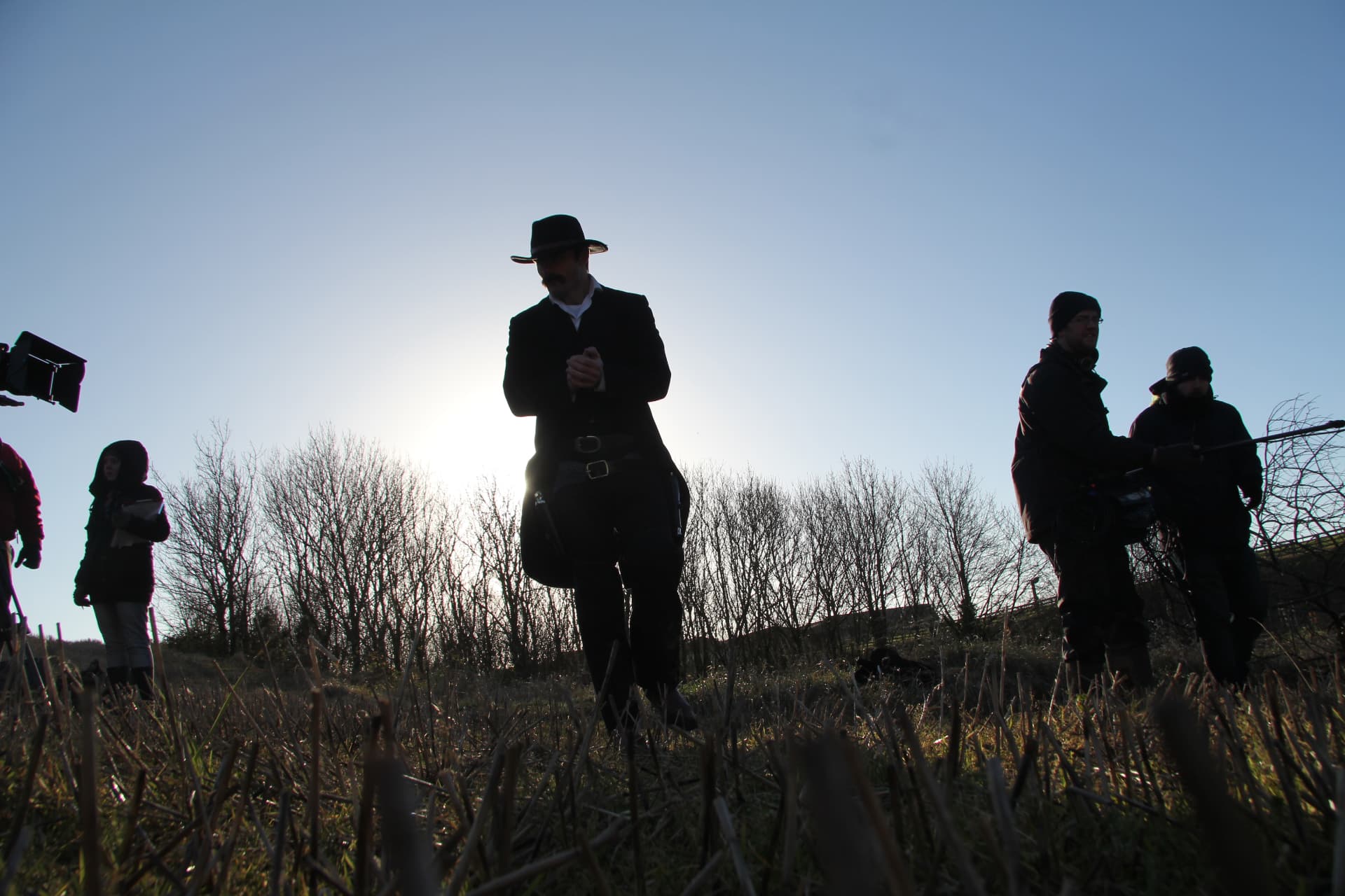 Silhouette of the lead actor and crew shooting into the low winter sun