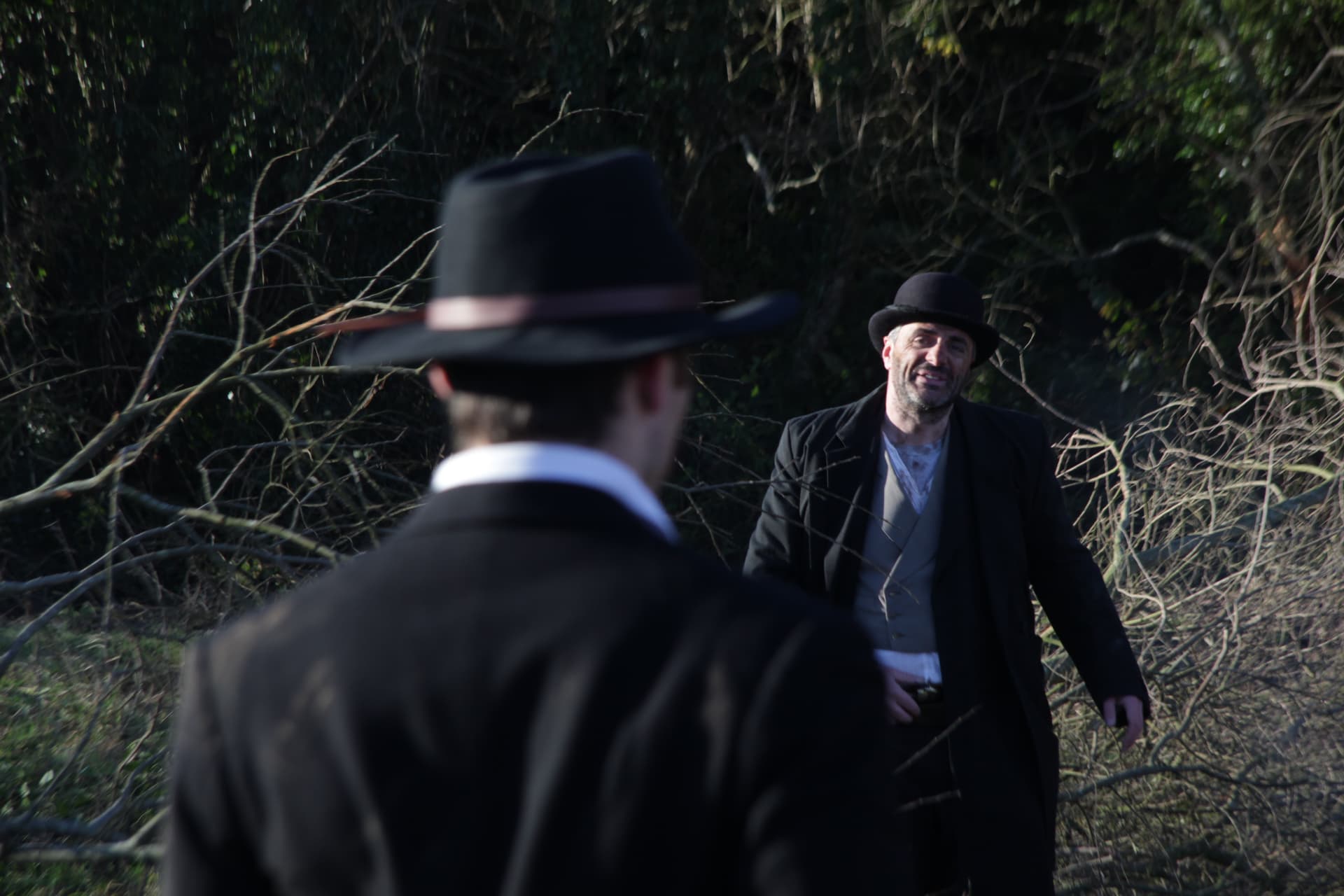 Two characters facing off in the hedgerow during filming